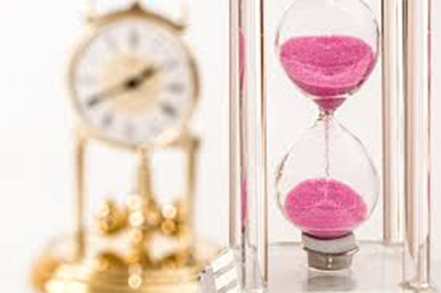 A hour glass with pink sand with a image of a clock in the far left corner