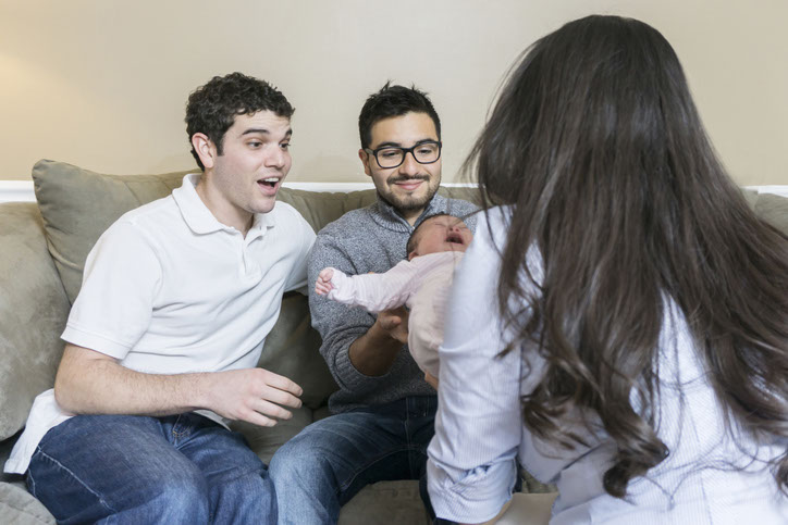 Young couple of fathers getting information on SafeSleep360° while the caseworker makes her home visit.